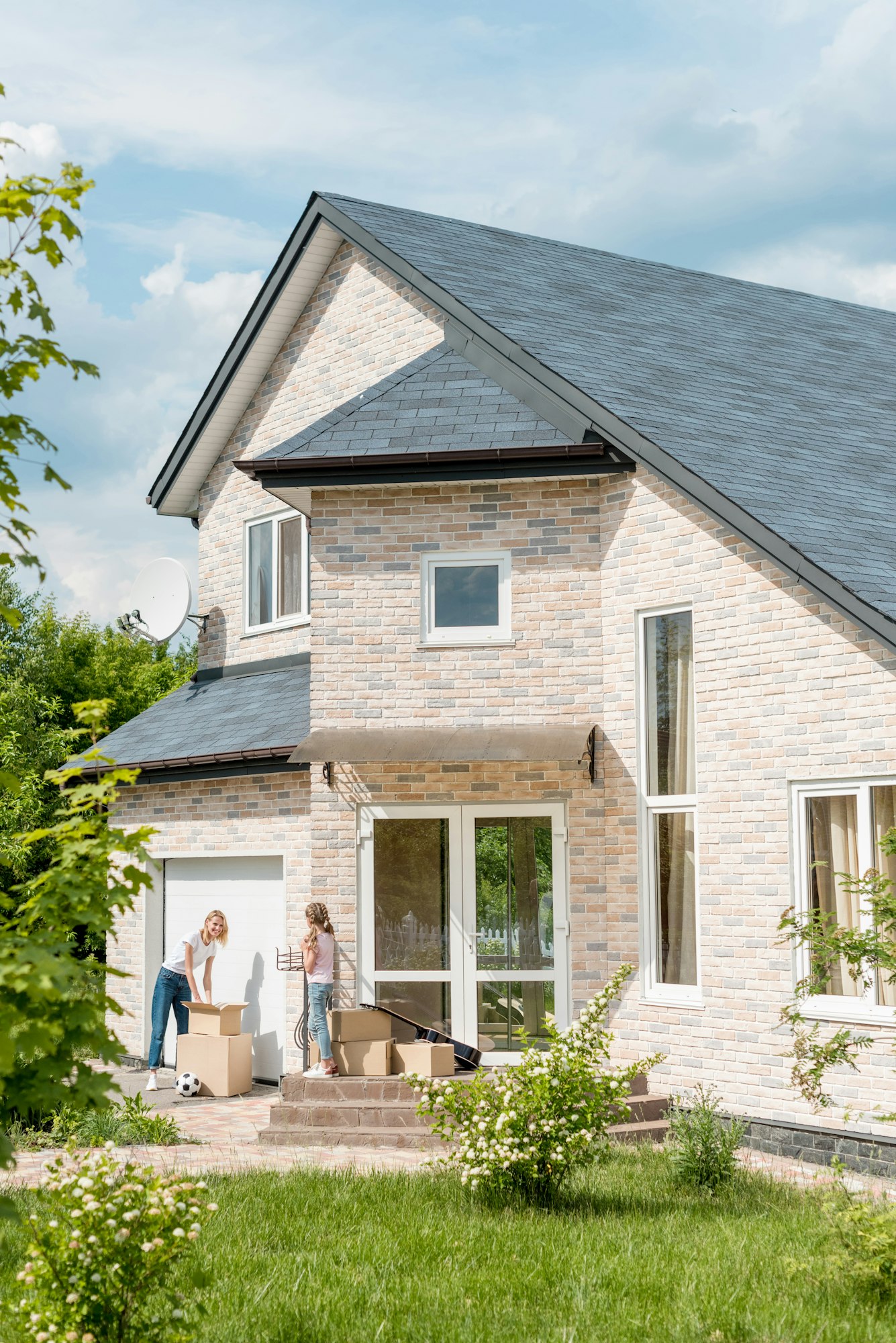 woman unpacking cardboard boxes while daughter standing on stairs of new cottage